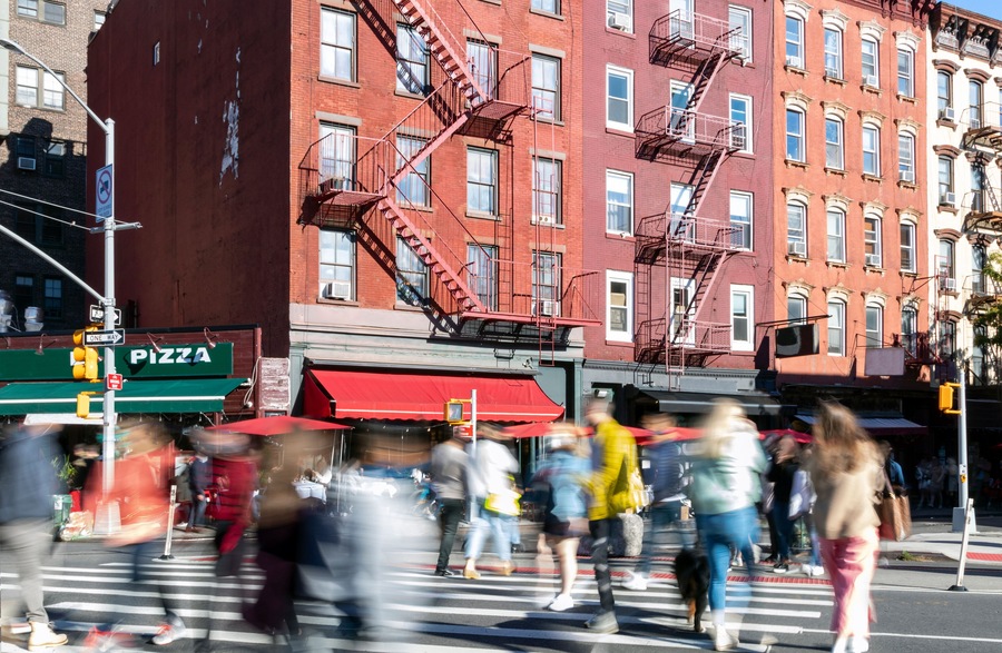 Busy street scene with crowds of people walking through the intersection on 7th Avenue and Bleecker in the Greenwich Village neighborhood of New York City