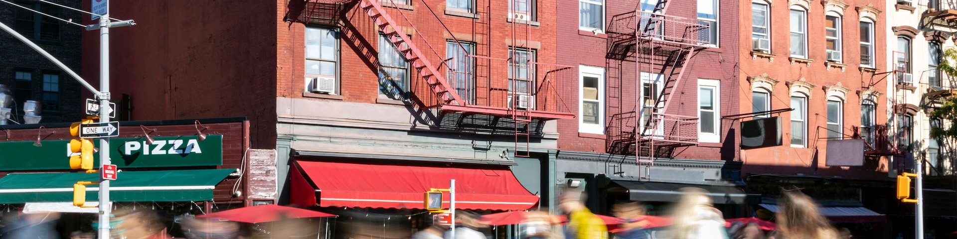 Busy street scene with crowds of people walking through the intersection on 7th Avenue and Bleecker in the Greenwich Village neighborhood of New York City