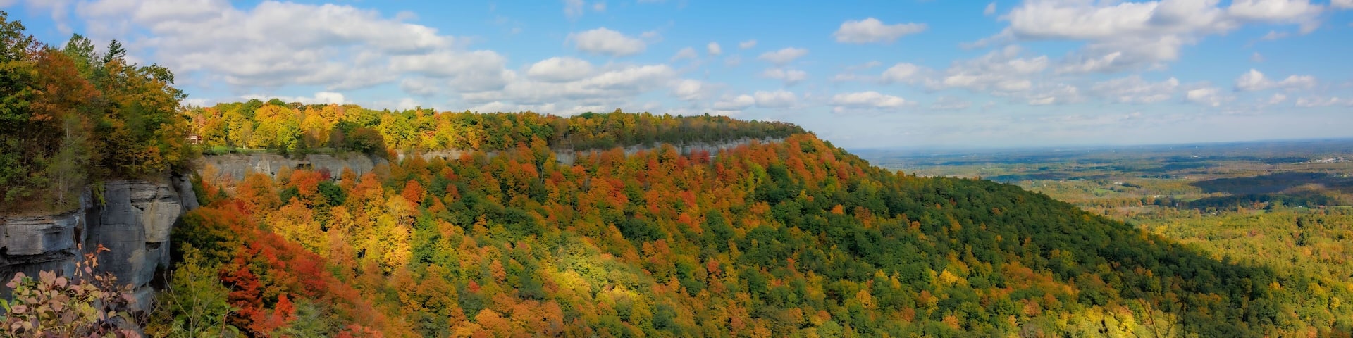 Panoramic scene of green mountains and trees in Thacher State Park in New York with blue sky