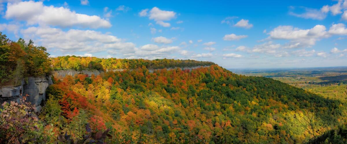Panoramic scene of green mountains and trees in Thacher State Park in New York with blue sky