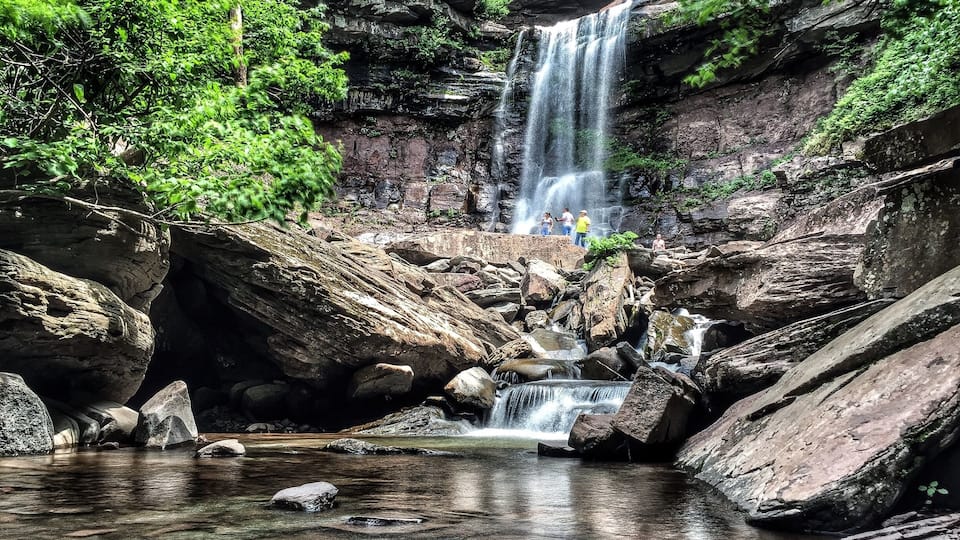 A waterfall cascading over rocks in a forested area with a small stream at the base.