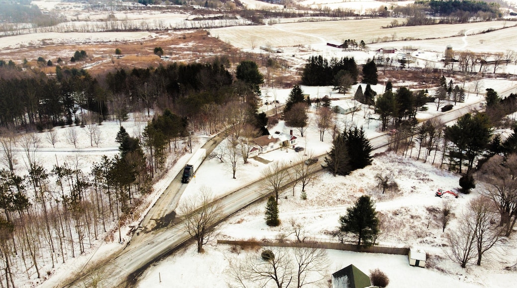 A rural landscape with snow-covered fields, a winding road, and scattered trees.
