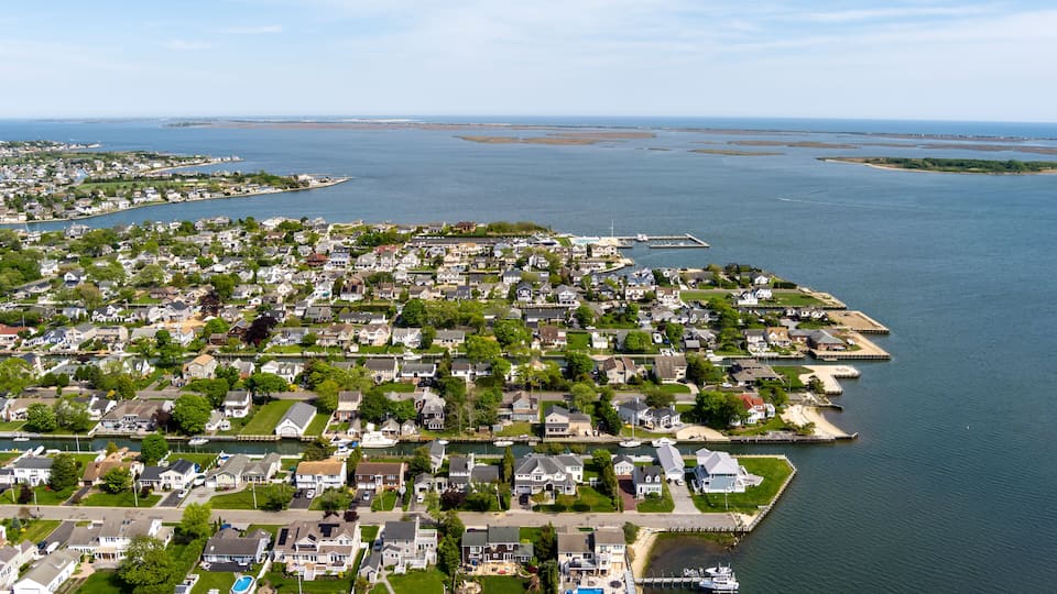 A coastal residential area with houses, a marina, and a large body of water.