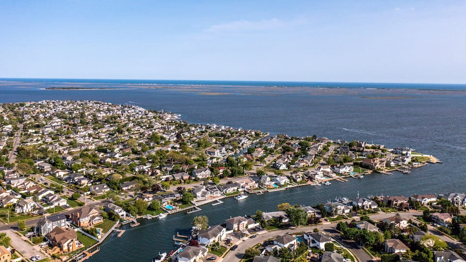 A coastal residential area with houses, a marina, and a large body of water.