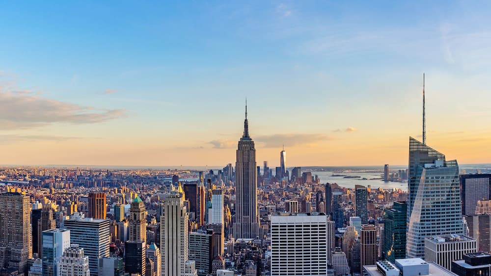 A cityscape with numerous skyscrapers, including the Empire State Building, under a clear sky.