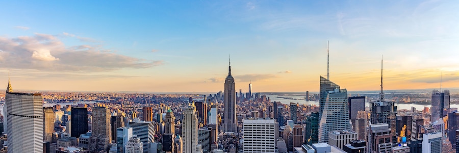 Un paisaje urbano con numerosos rascacielos, incluyendo el Empire State Building, bajo un cielo despejado.