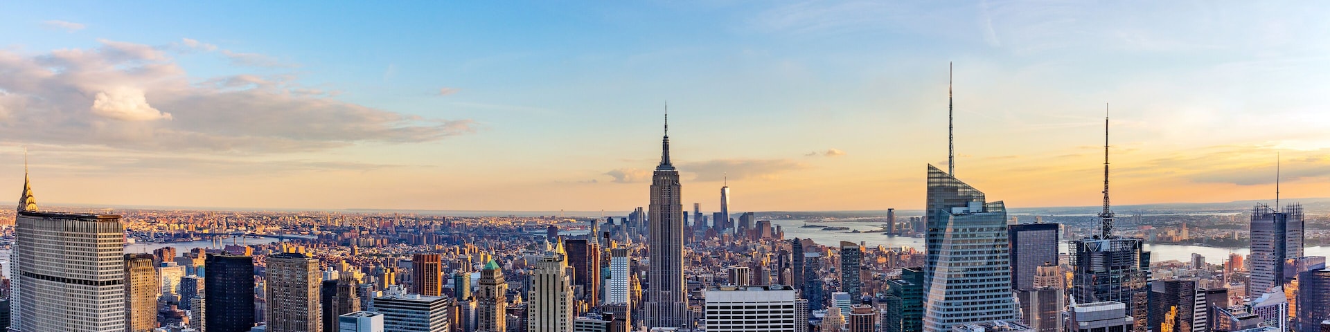Un paisaje urbano con numerosos rascacielos, incluyendo el Empire State Building, bajo un cielo despejado.