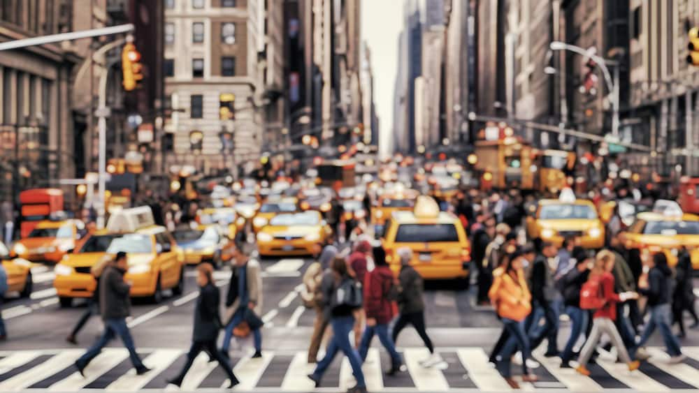 Blurred Busy street scene with crowds of people walking across an intersection in New York City. Blurred image, wide panoramic view of the road with people