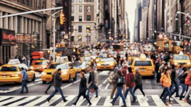Blurred Busy street scene with crowds of people walking across an intersection in New York City. Blurred image, wide panoramic view of the road with people