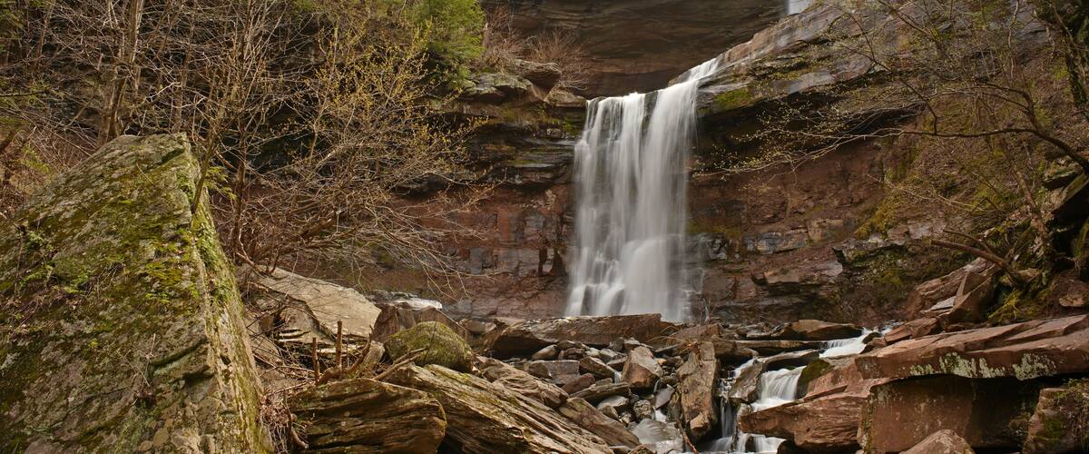 A waterfall cascading down a rocky cliff surrounded by trees.