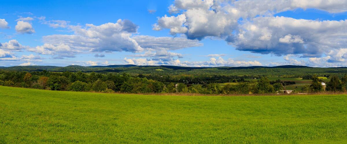 Hudson Valley skyline with farm land and meadows on a cloud filled summer day.