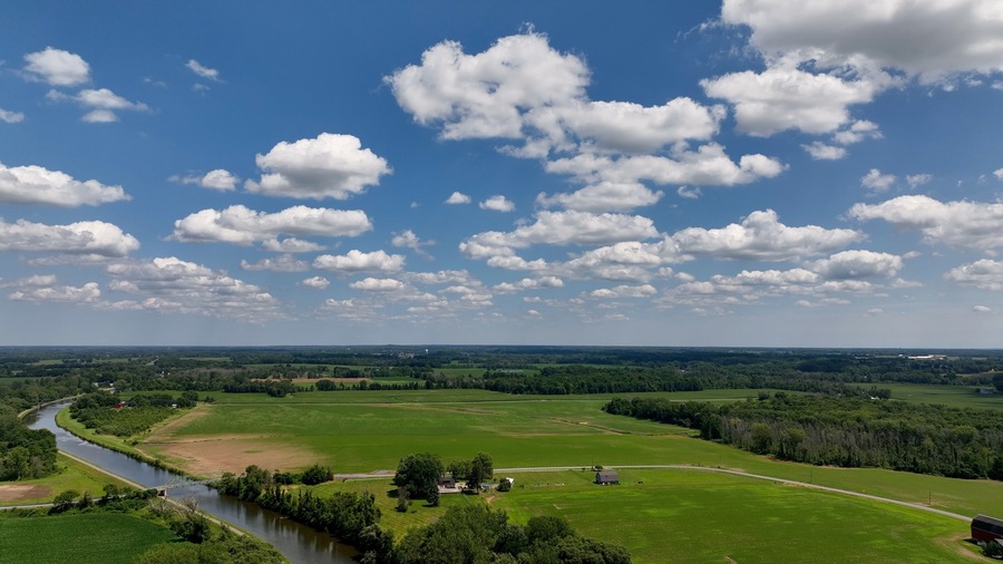 Landscape with green farmland by Eire Canal in Up State New York under blue sky and clouds on summer day