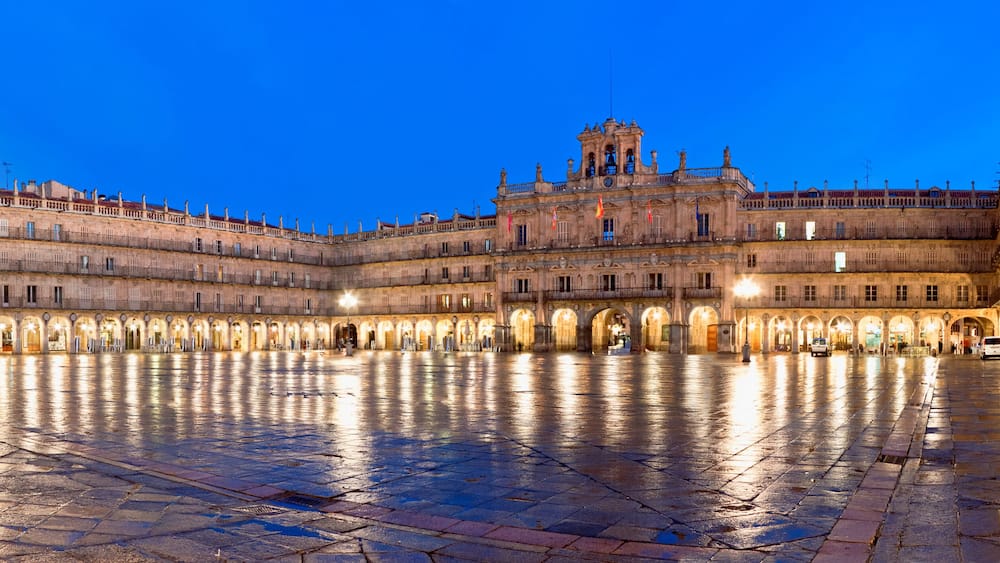 A historic plaza with a large open space, ornate buildings, and a prominent bell tower.