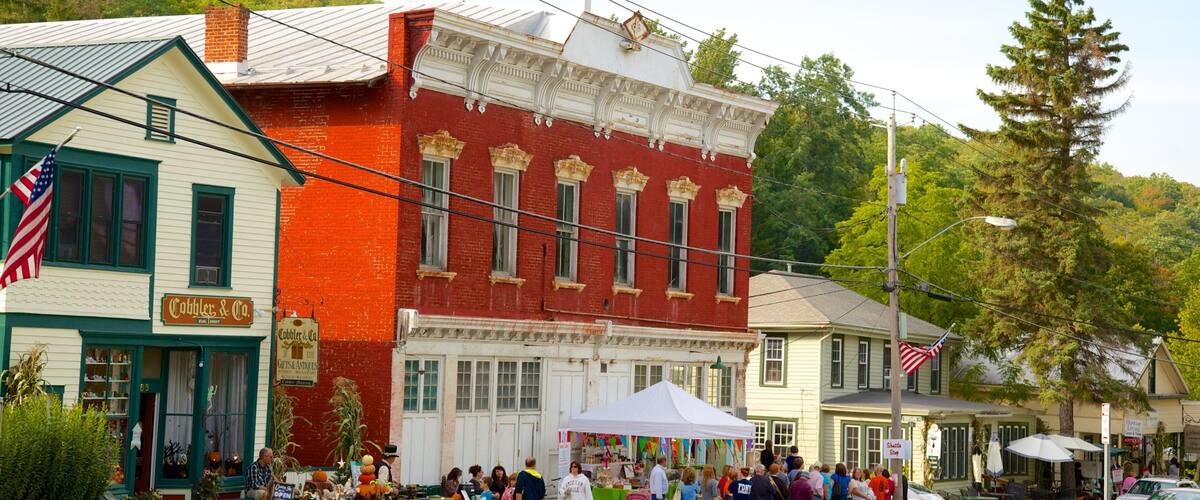 A historic building with a red facade and green trim, a white building with a green awning, and a white building with a green roof.