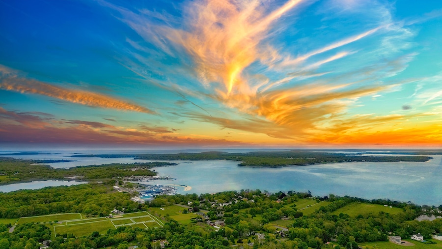 A coastal landscape with a sunset, a marina, and a residential area.