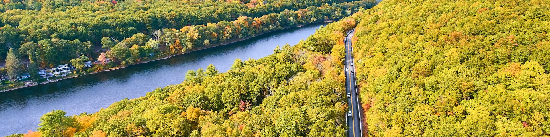 A river winding through a forested valley with a road running alongside it.