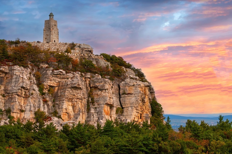 Una torre di pietra su una scogliera con un cielo al tramonto.
