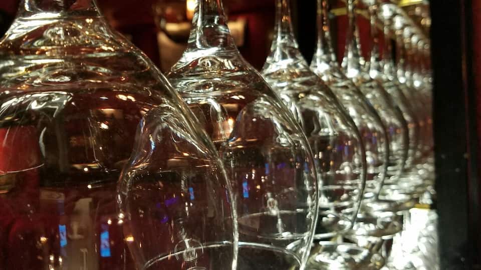 A row of empty wine glasses on a reflective surface.