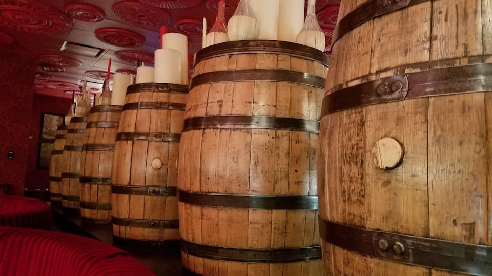 Wooden barrels lined up in a room with red ceiling decorations.