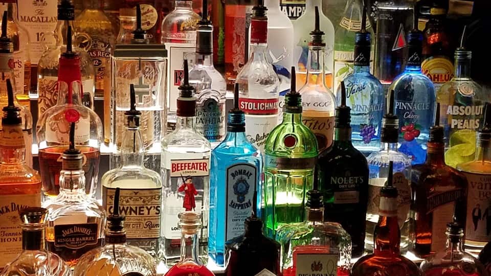 A variety of liquor bottles on a shelf.