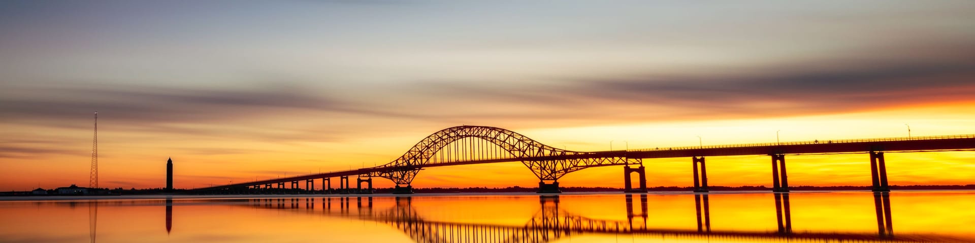 Eine Brücke im Abendrot mit Spiegelbild im ruhigen Wasser.