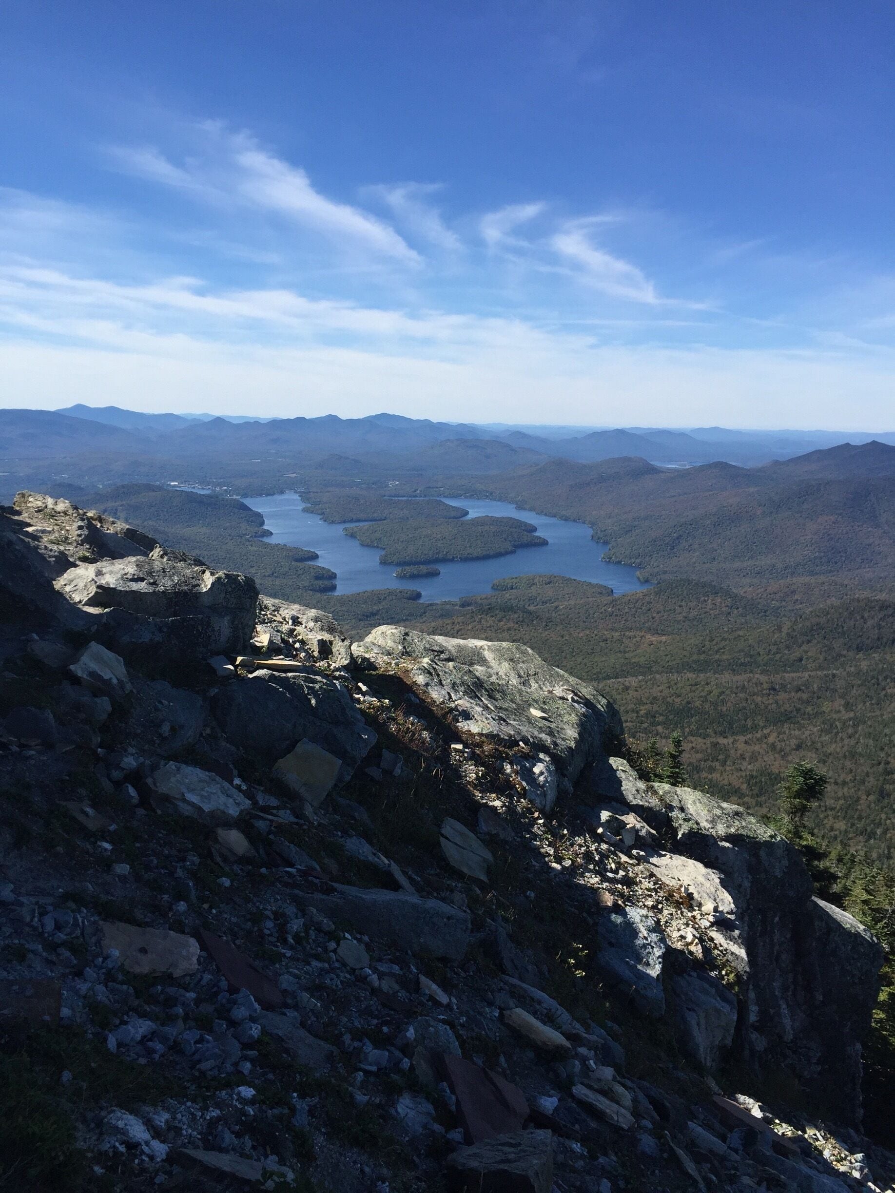 A mountainous landscape with rocky terrain and a lake surrounded by forested hills.