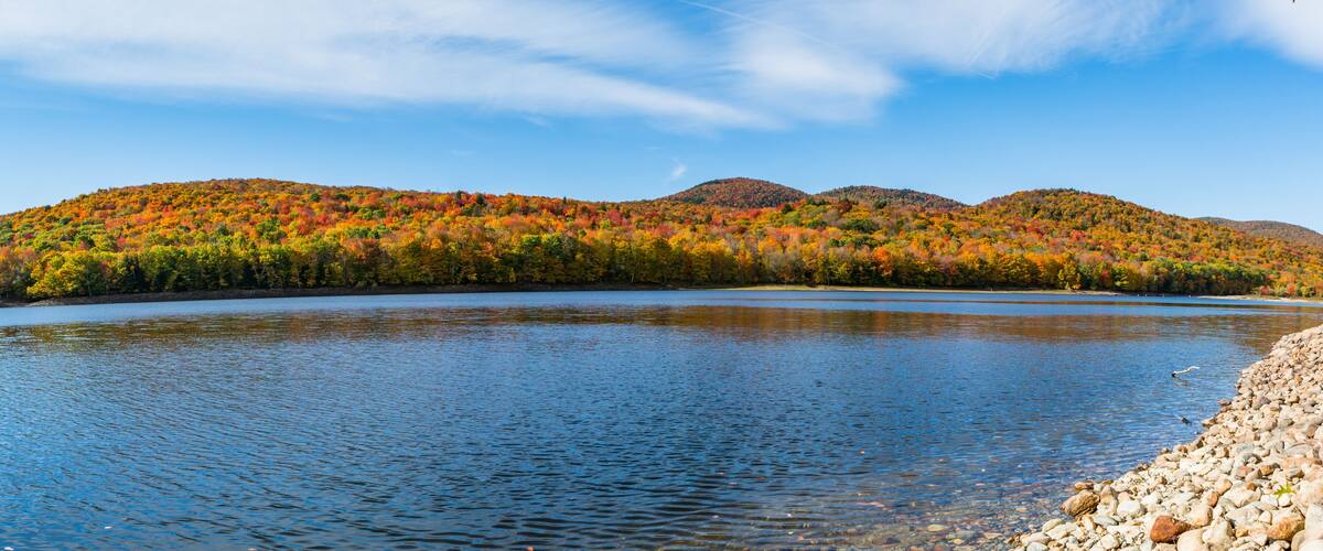 A lake surrounded by colorful autumn foliage and distant mountains.