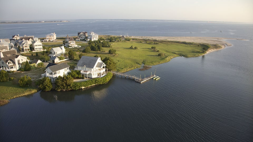 A coastal residential area with houses, a pier, and a large body of water.