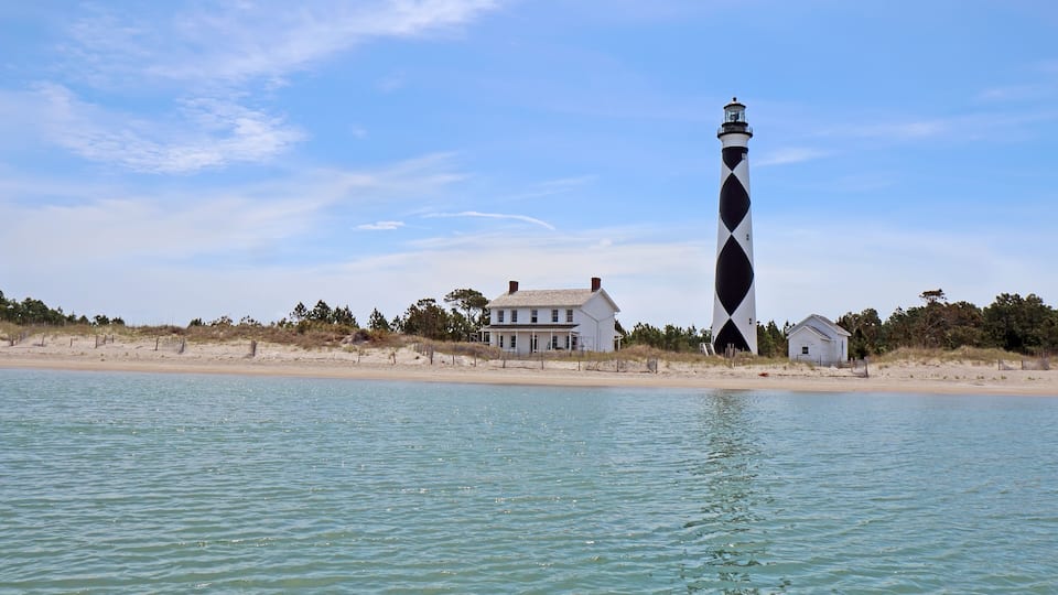 A lighthouse, a beach, and a house by the water.