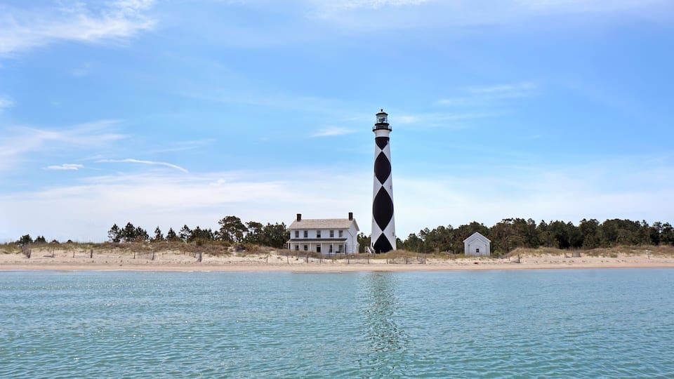 A lighthouse, a beach house, and a small cabin by the water.