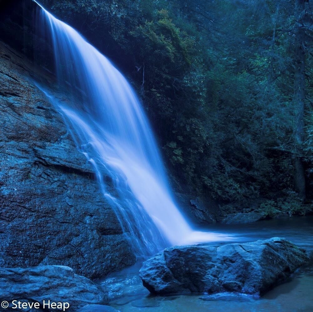 A waterfall cascading over rocks in a forested area.