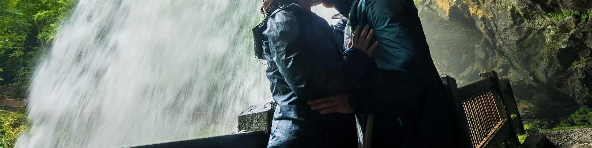 Couple kisses behind Dry Falls water fall