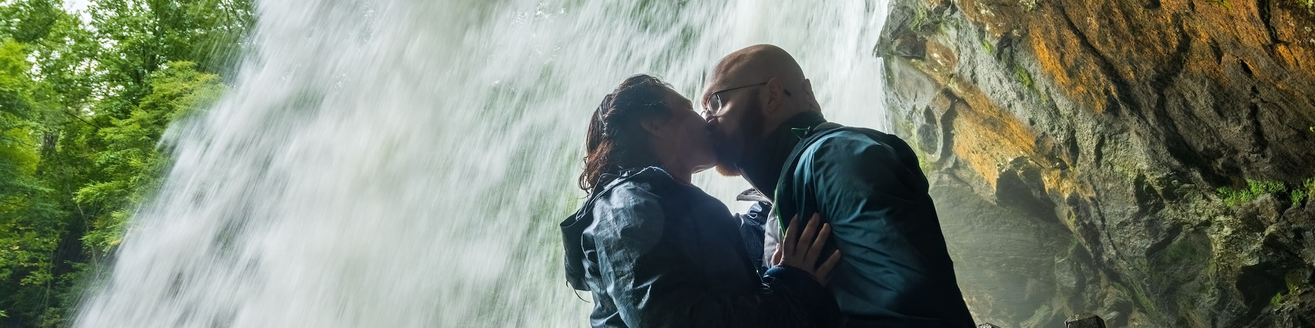 Couple kisses behind Dry Falls water fall