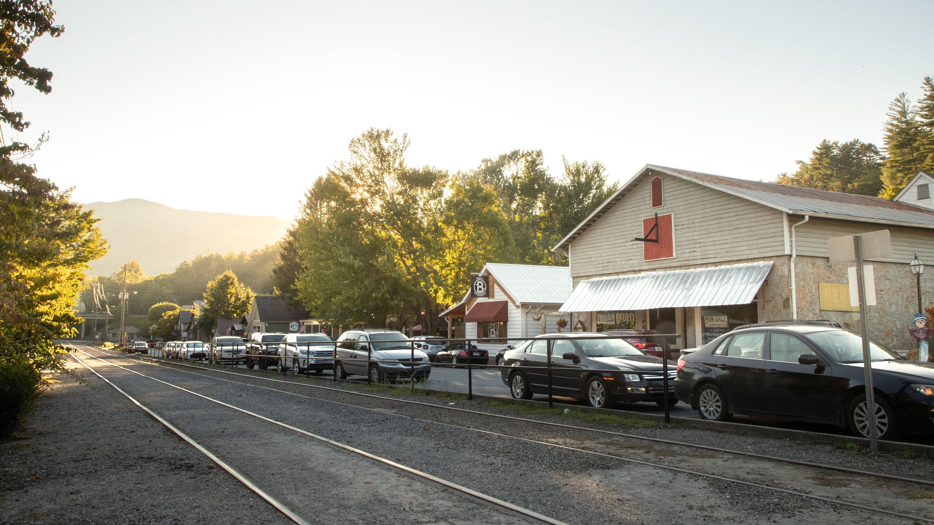 A railway track with cars parked beside it, a building with a 'B' sign, and a 'NEW' sign on the side.
