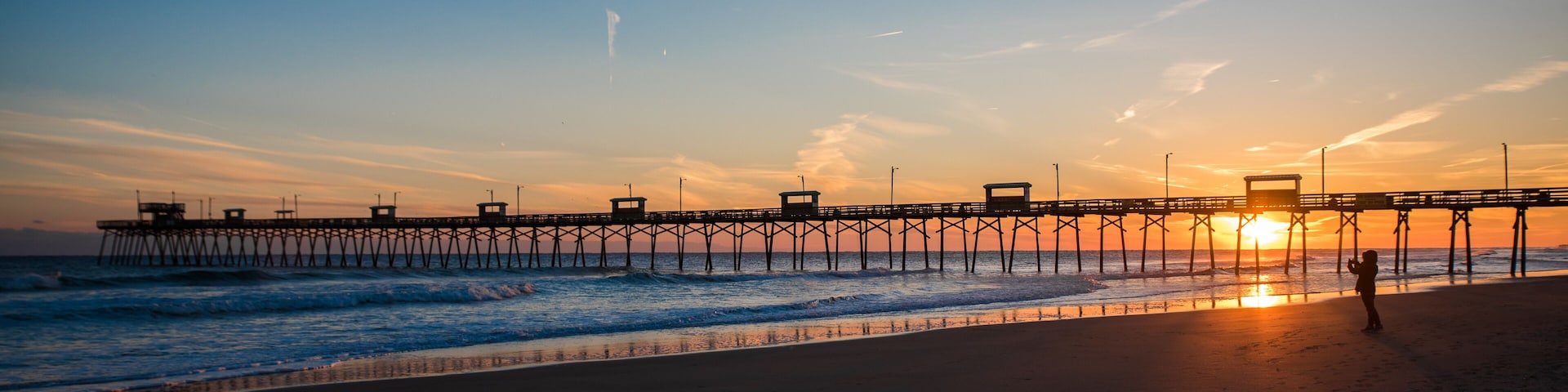 A pier extending into the ocean at sunset.