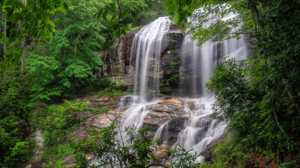 A waterfall cascading over rocks surrounded by lush greenery.