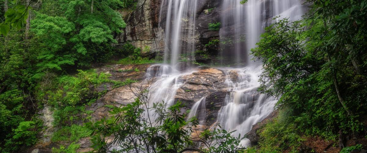 A waterfall cascading over rocks surrounded by lush greenery.
