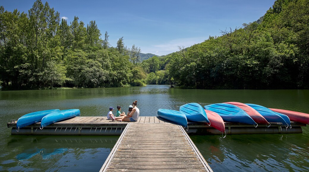 familia sentada en un embarcadero de un lago entre montañas