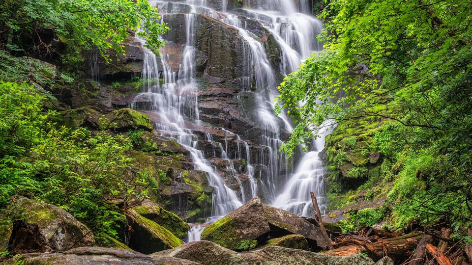 A multi-tiered waterfall surrounded by lush green foliage.