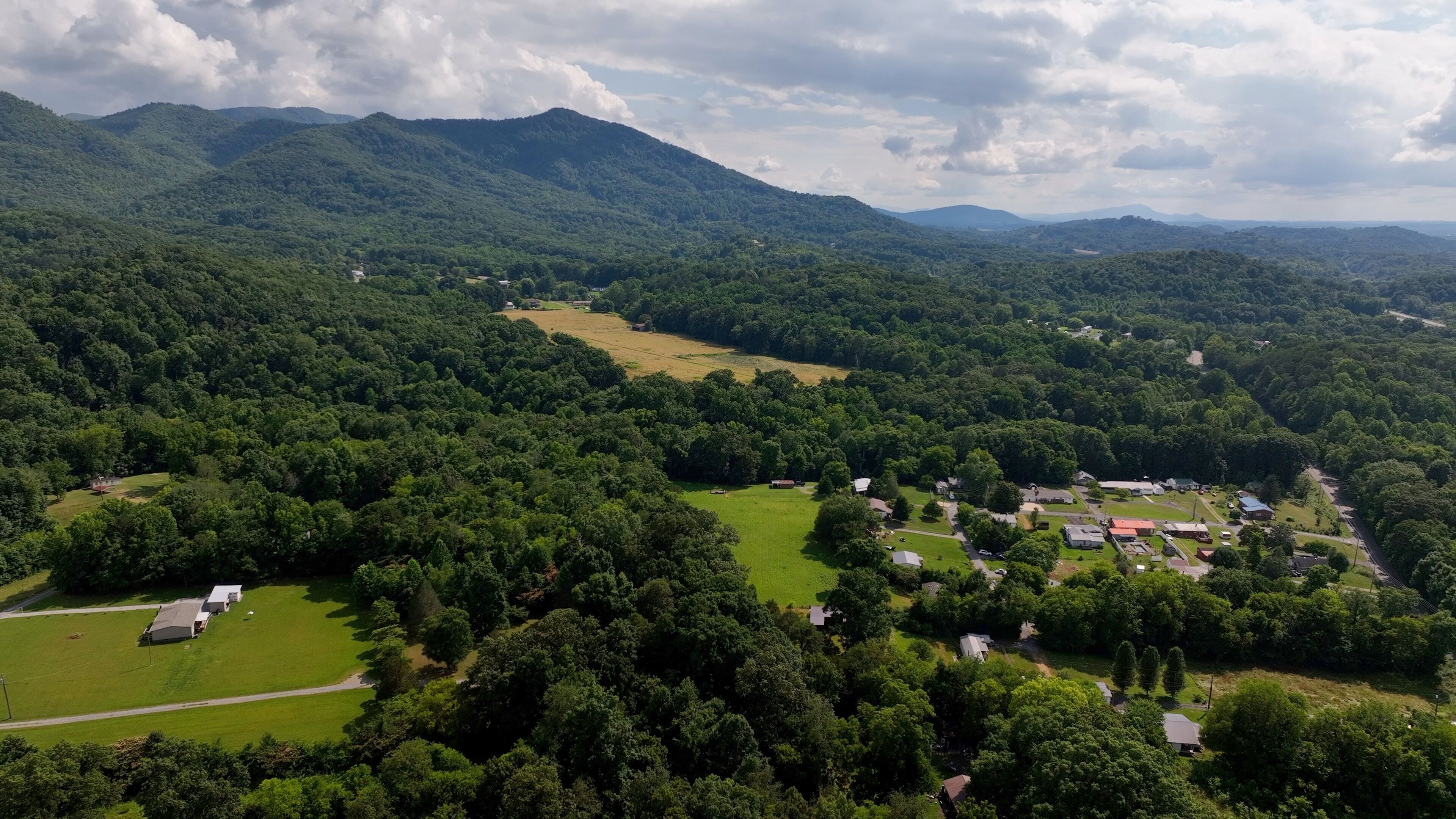 Living in a peaceful small town by the Great Smoky Mountains with green fields and trees under blue sky with clouds in North Carolina