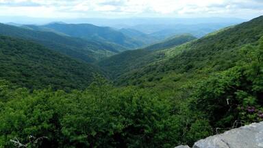 A mountainous landscape with dense green forests and rolling hills.