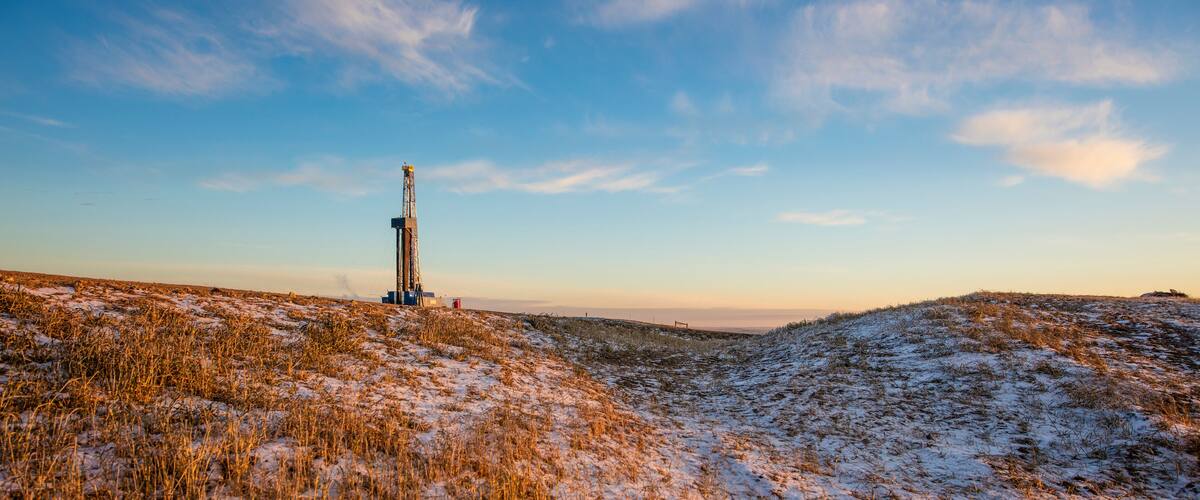 A snowy landscape with a drilling rig in the distance.