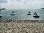 Una costa rocciosa con jet ski sull'acqua.