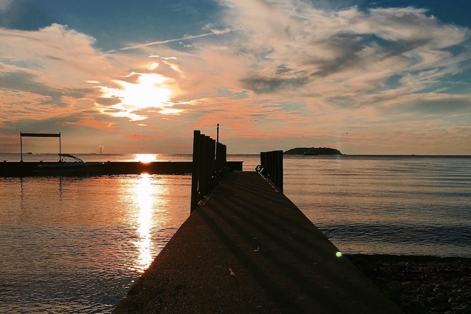 Un atardecer sobre un mar tranquilo con un muelle que se adentra en el agua.
