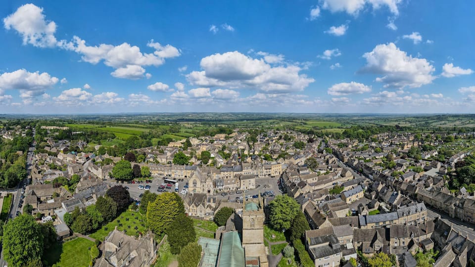 A historic town with a central square, surrounded by green fields and a clear blue sky.