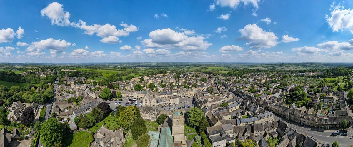 A historic town with a central square, surrounded by green fields and a clear blue sky.