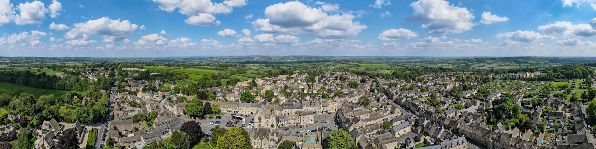 A historic town with a central square, surrounded by green fields and a clear blue sky.