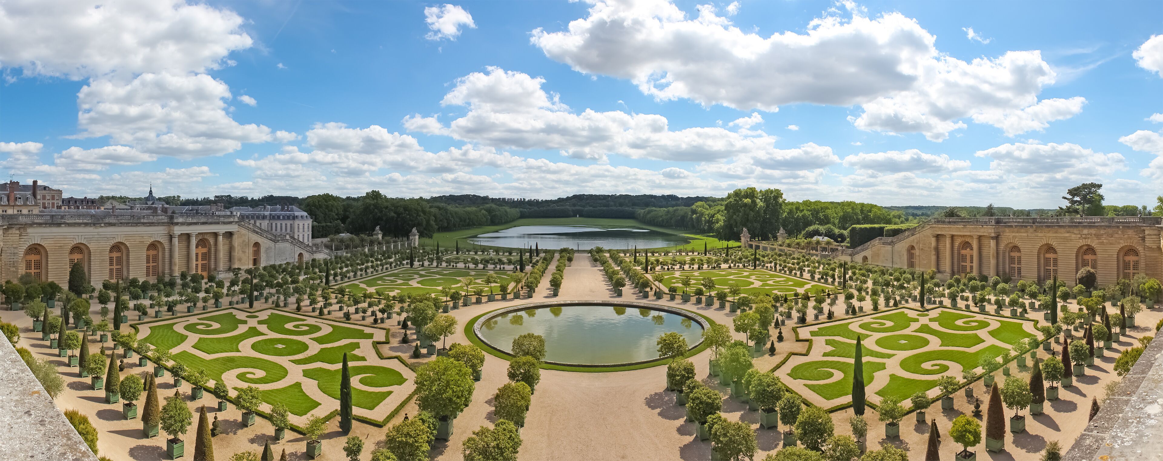 A formal garden with symmetrical pathways, a central pond, and classical architecture.