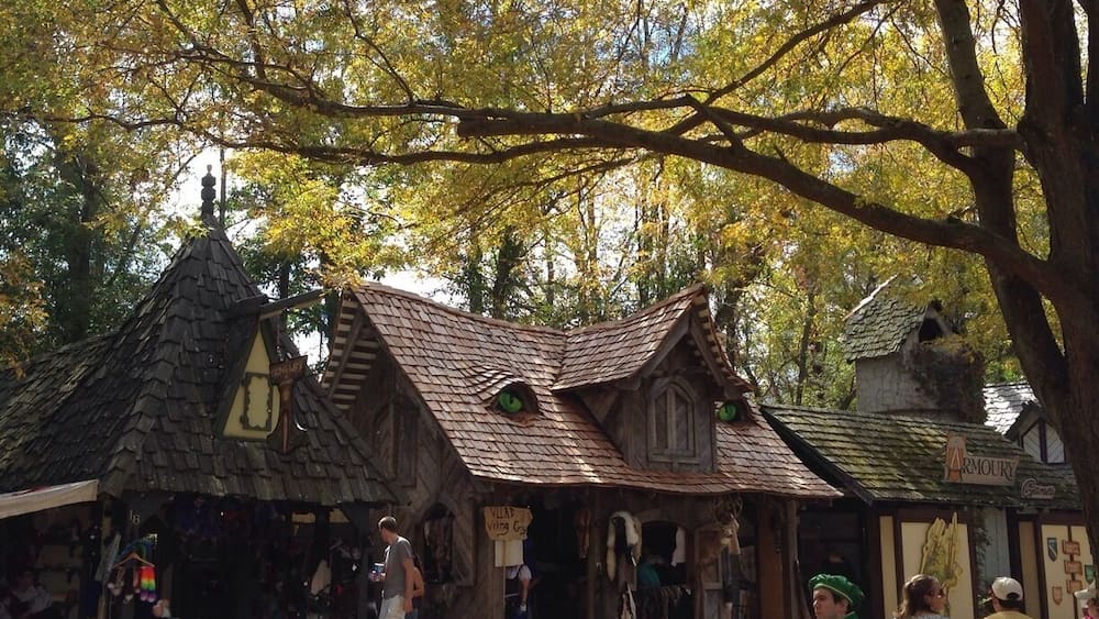 A rustic building with a steeply pitched roof and a sign that reads "Armoury."