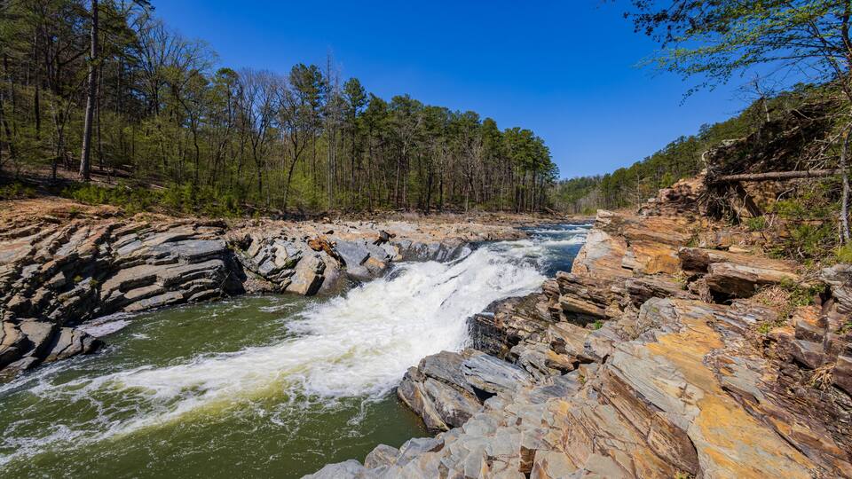 A river flowing through a rocky gorge with a forested area on both sides.